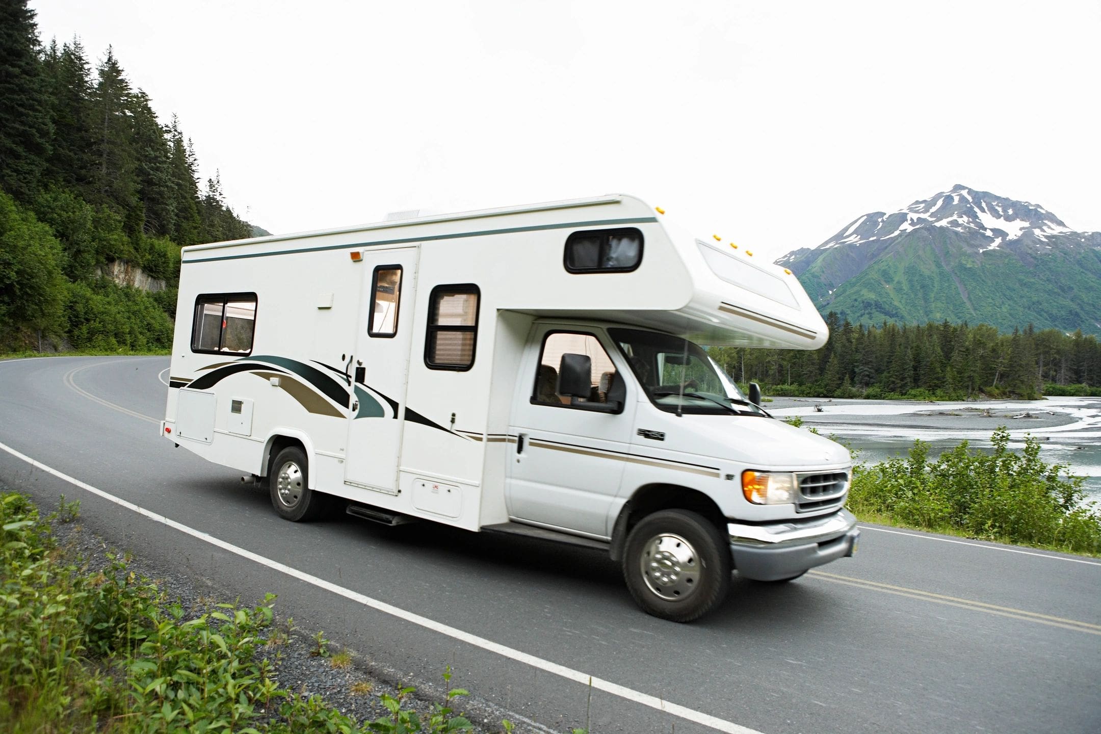 A white rv is driving down the road