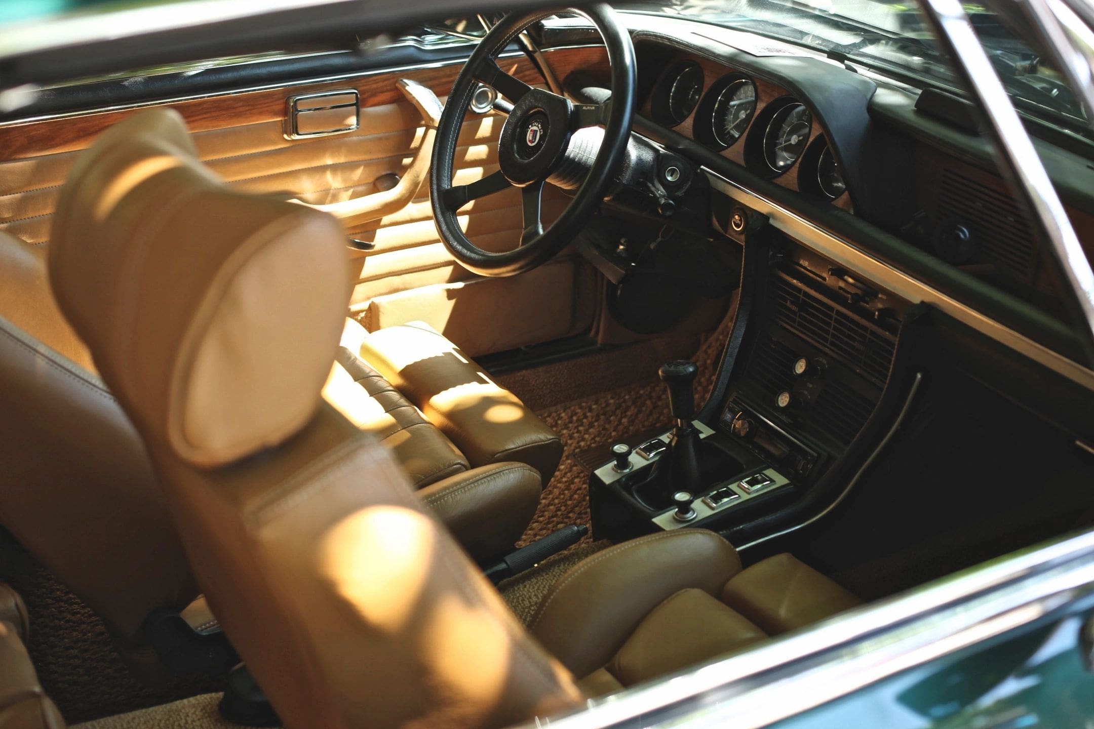 A car with tan leather seats and wood trim.