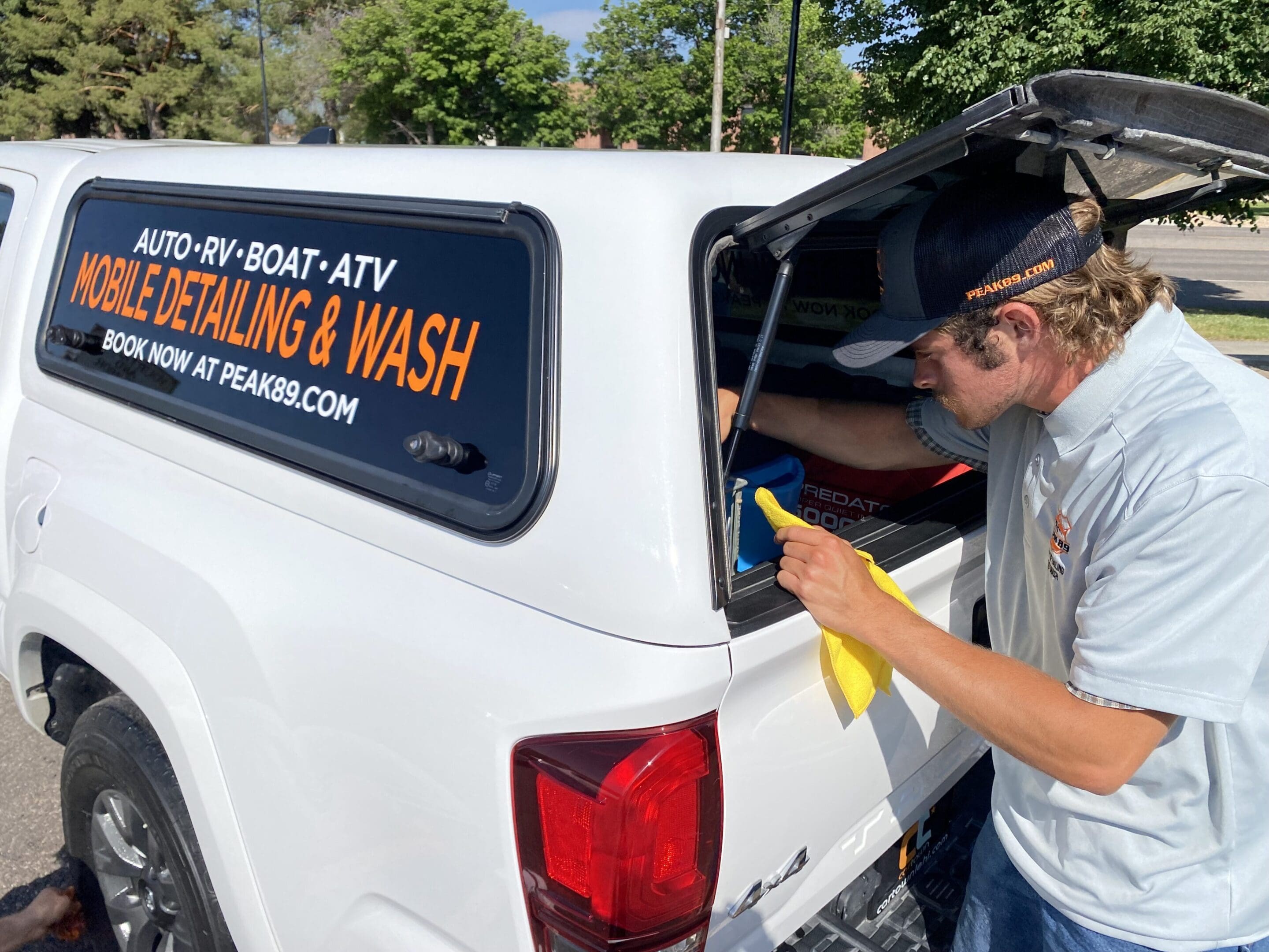 A man is cleaning the back of his truck.