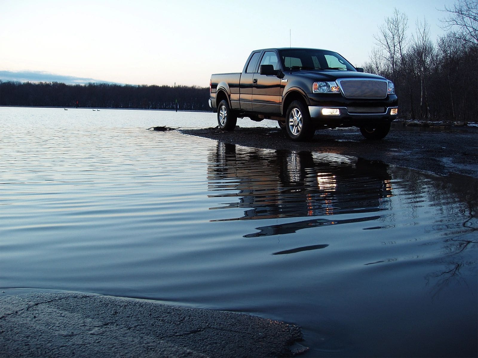 A truck is driving through water on the road.